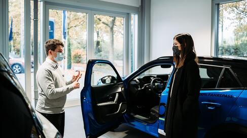 Selina neben Peugeot e-2008 im Autohaus Koch