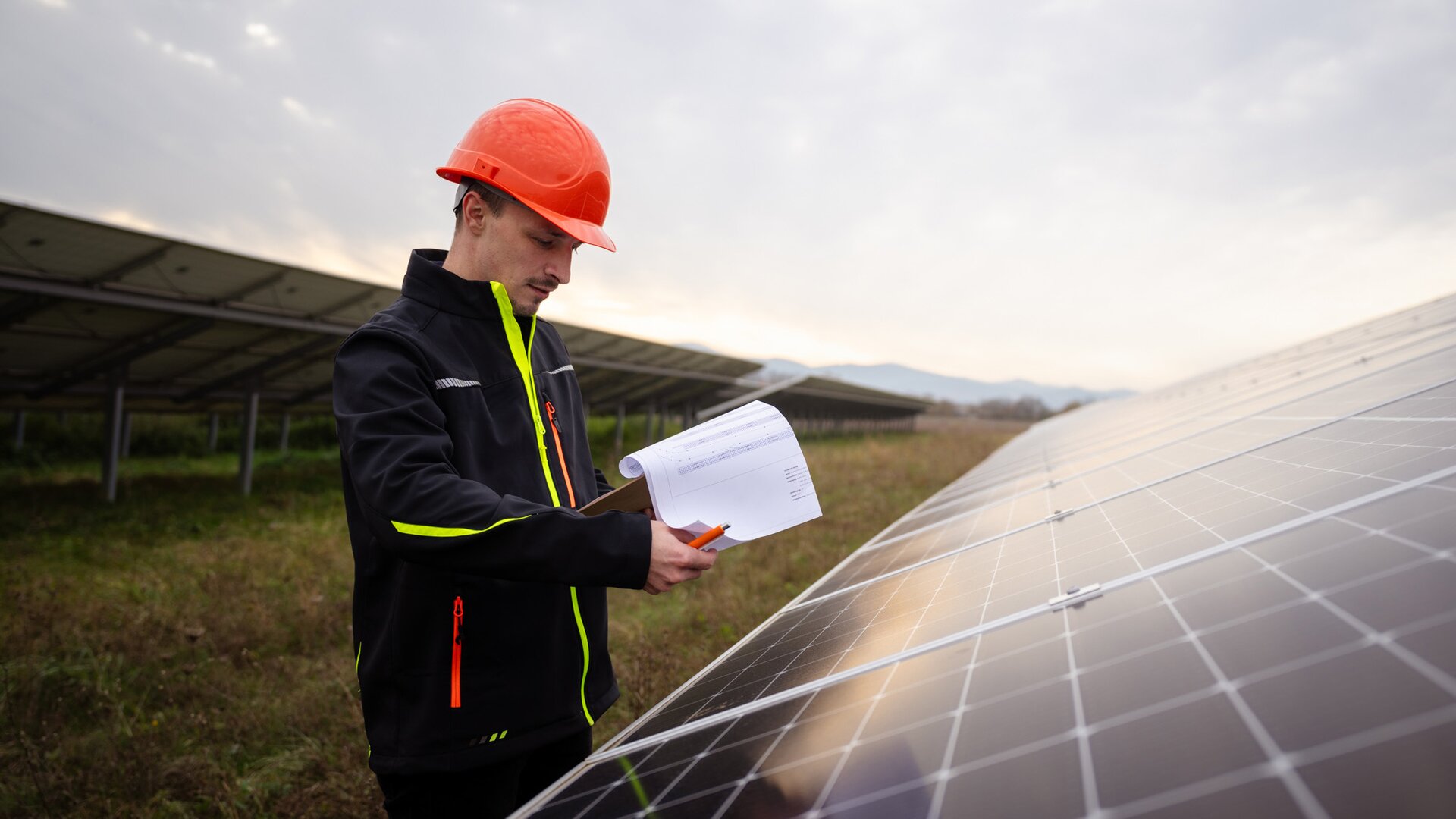 Mitarbeiter an Solaranlage mit Bauplänen in der Hand