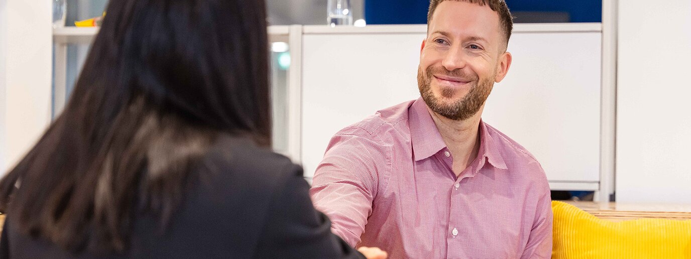 Zwei Kolleg*innen, geben sich die Hand