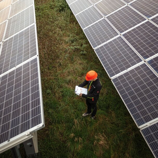 Aufnahme von oben auf einen Mitarbeiter, umgeben von Solarzellen