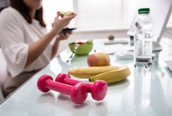 Obst und Hanteln auf Büroschreibtisch als Symbol für Gesundheit