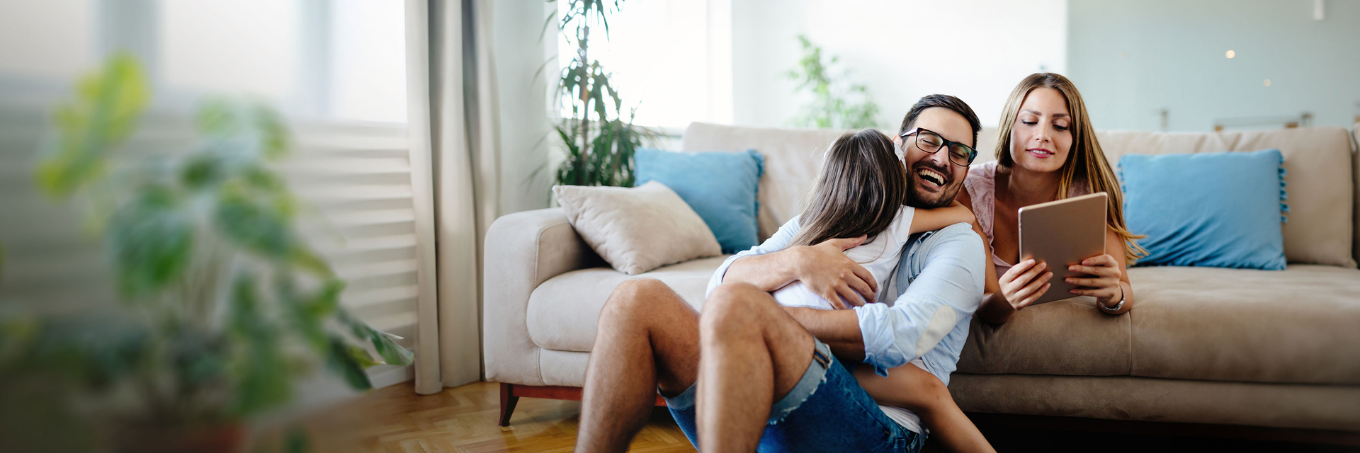 Glückliche Familie auf Couch mit Tablet