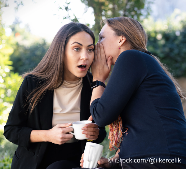 Frauen flüstern sich etwas ins Ohr