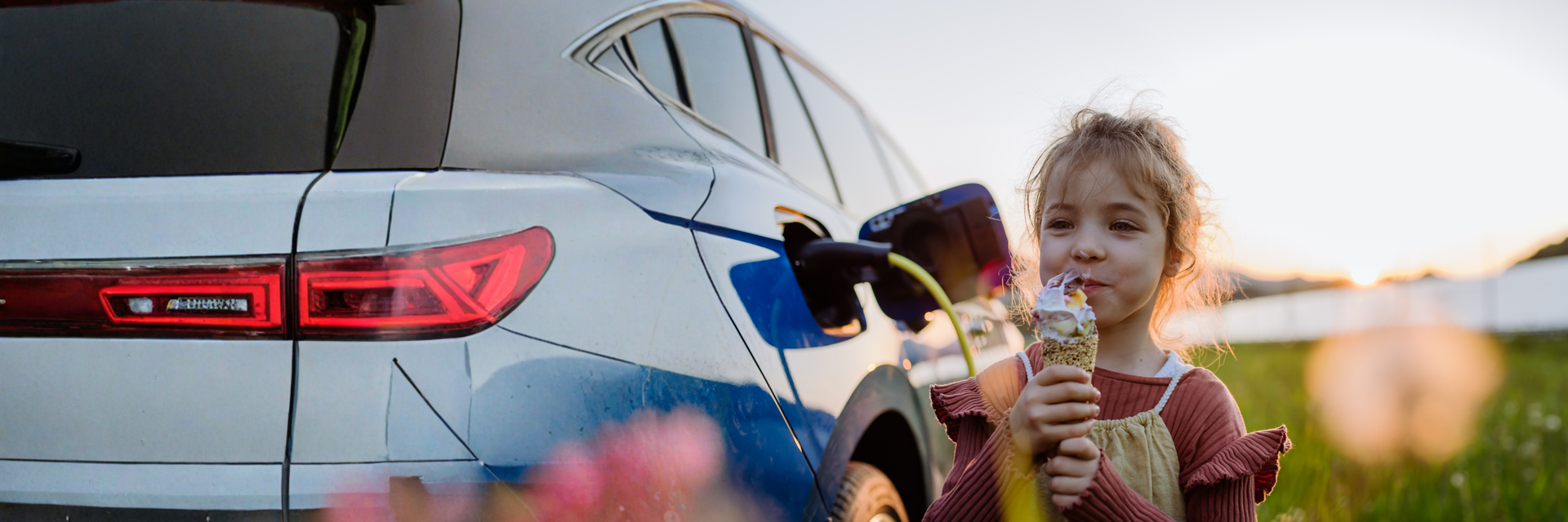 Kind mit Eis steht am Elektroauto