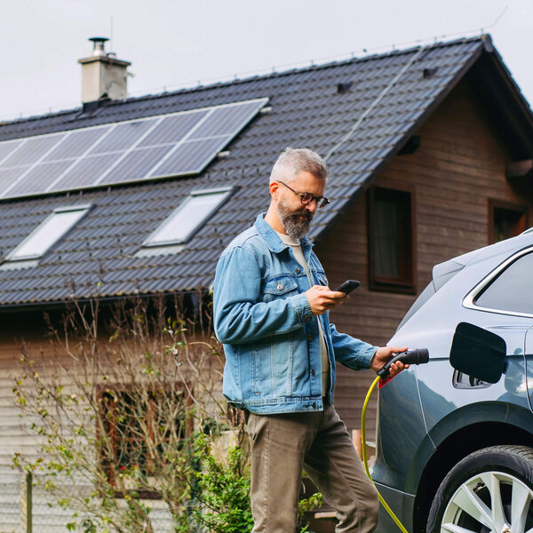 Mann steuert über sein Handy seine Solaranlage und die Wallbox | © Bildnachweis: iStock.com/Halfpoint