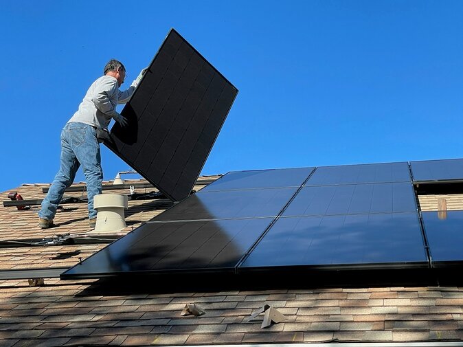 Solarmonteur steht auf dem Dach und befestigt eine Solaranlage