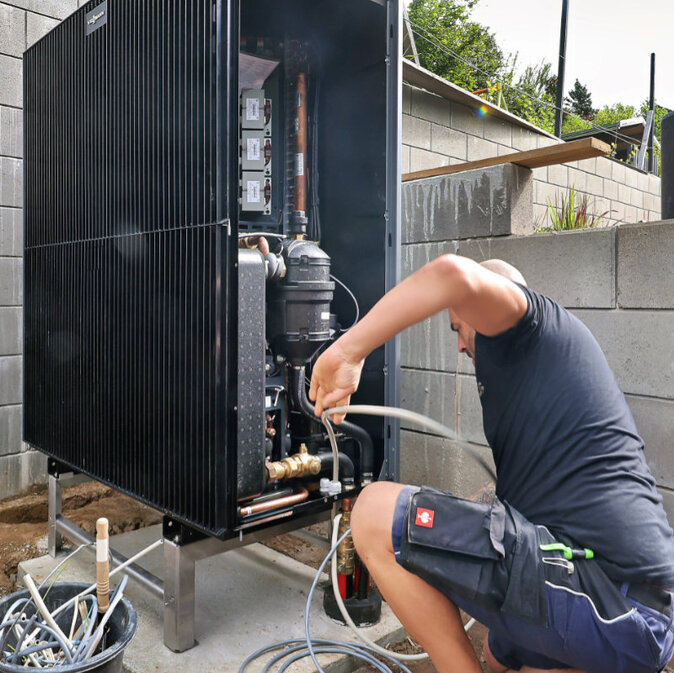 Techniker wartet Wärmepumpe am Haus