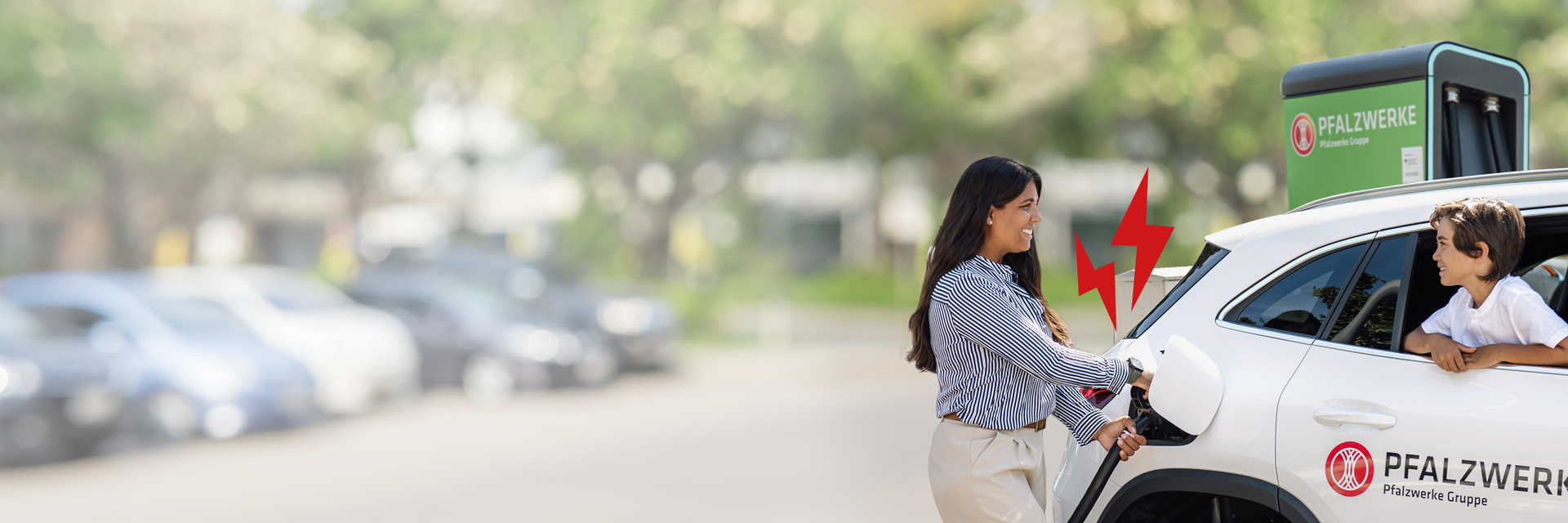 Eine fröhliche Frau lädt ihr E-Auto an einer Ladesäule der PFALZWERKE