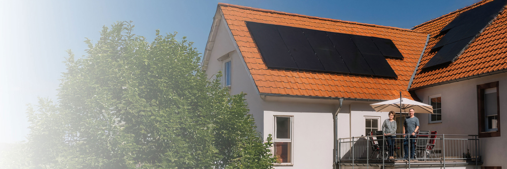 Paar steht auf dem Balkon im Hintergrund die Solaranlage | © Bildnachweis: Pfalzwerke/Patrick Junker