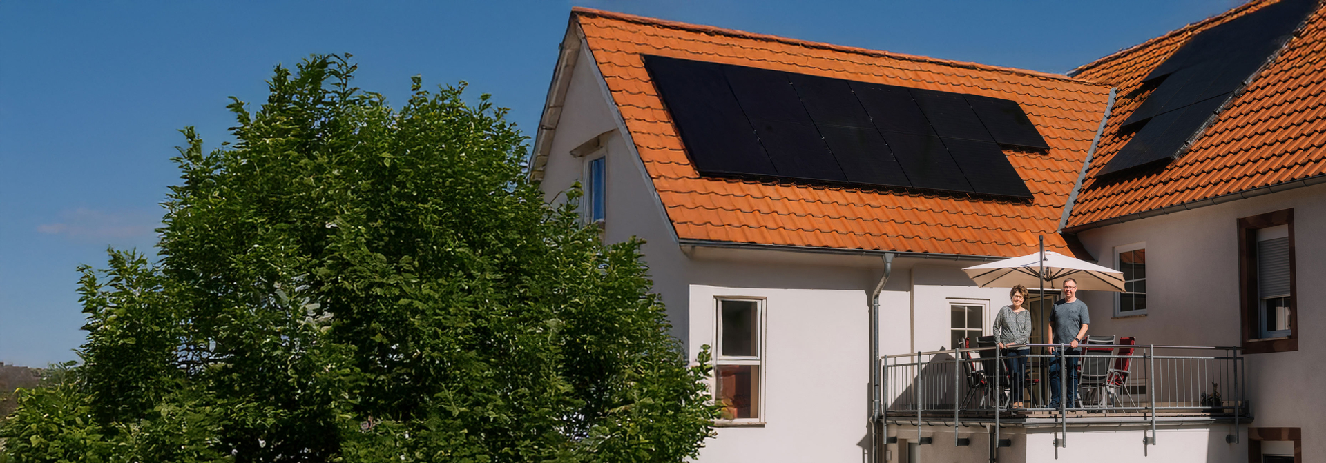 Paar steht auf dem Balkon im Hintergrund die Solaranlage | © Bildnachweis: Pfalzwerke/Patrick Junker