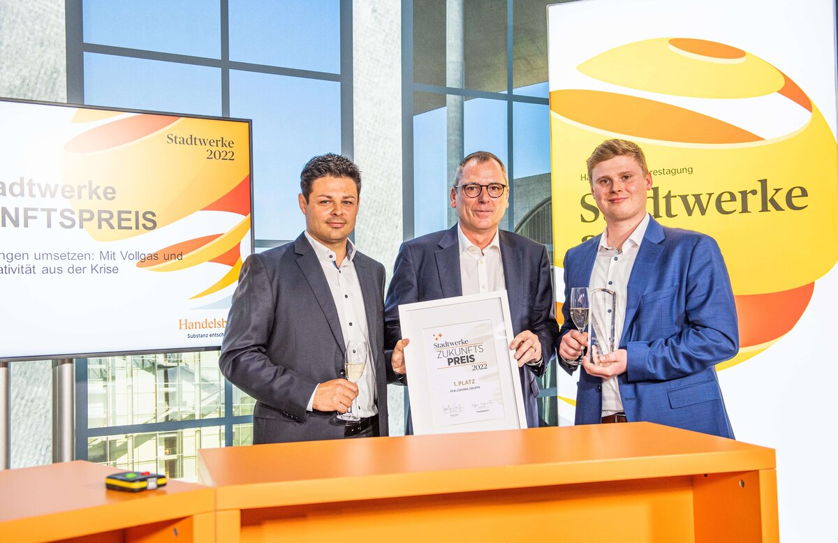 Drei Männer halten die Auszeichnung "Zukunftspreis 2022" in die Kamera. 