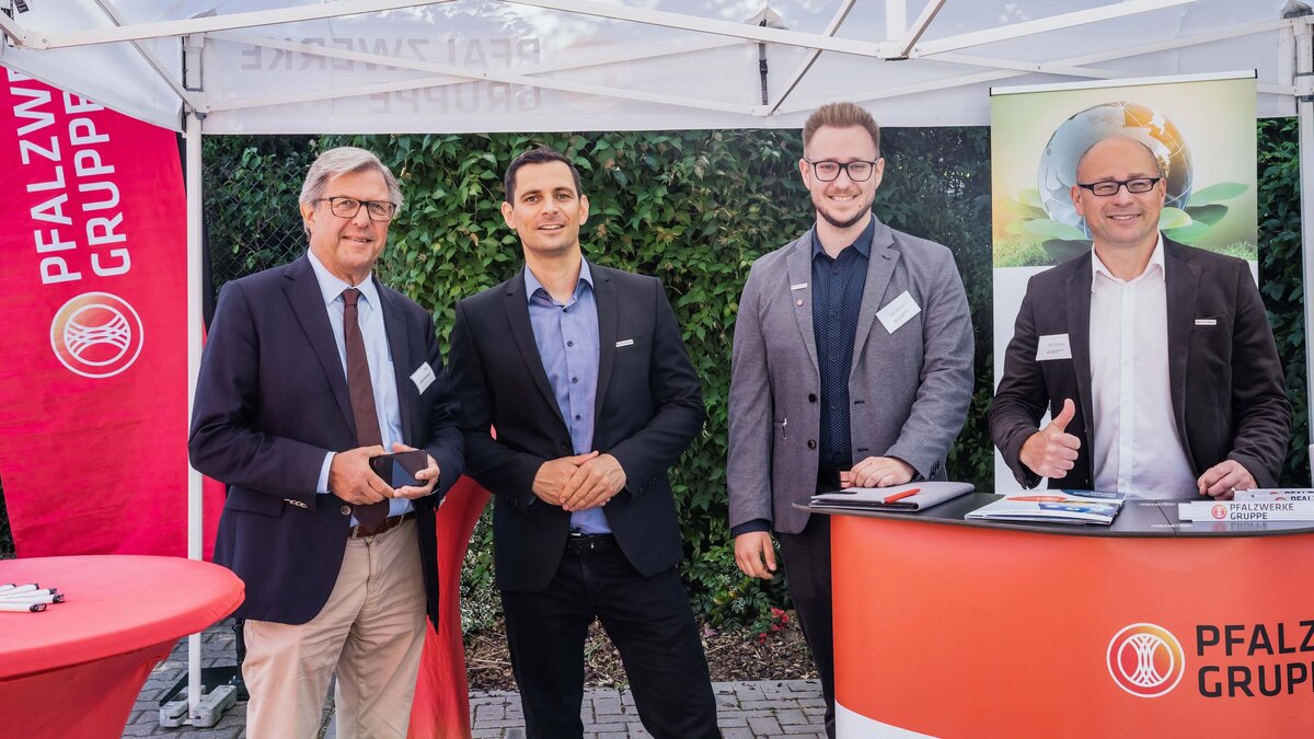 Vier Männer stehen an einem Messestand der Pfalzwerke. 