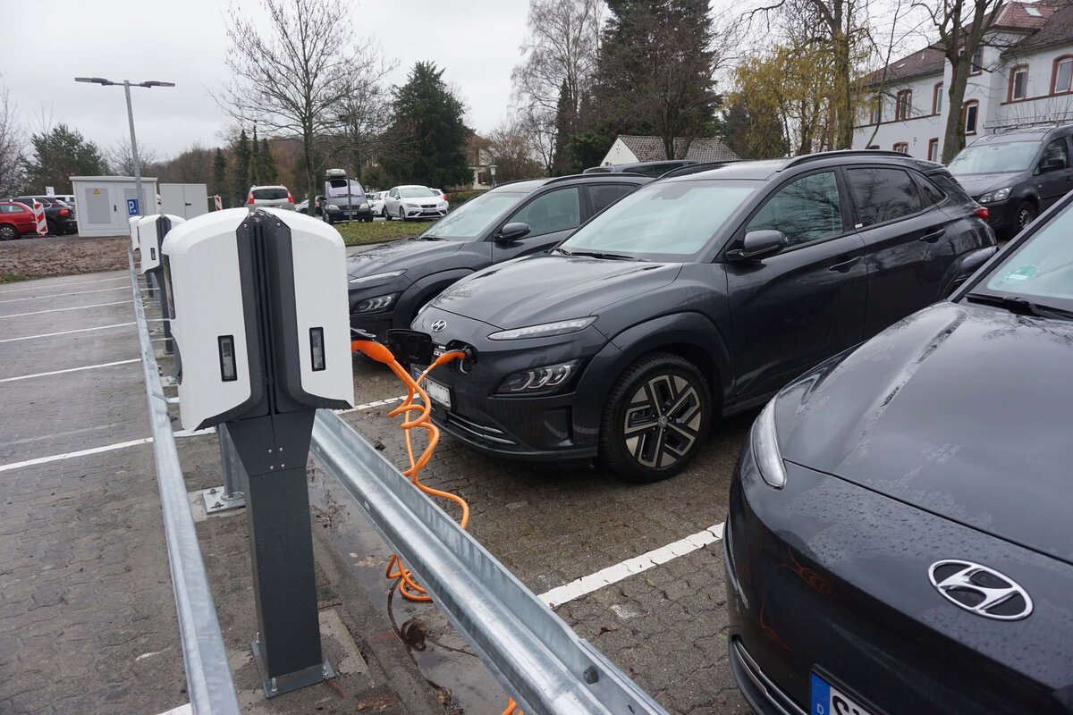 Das Bild zeigt drei E-Autos an Ladestationen. 
