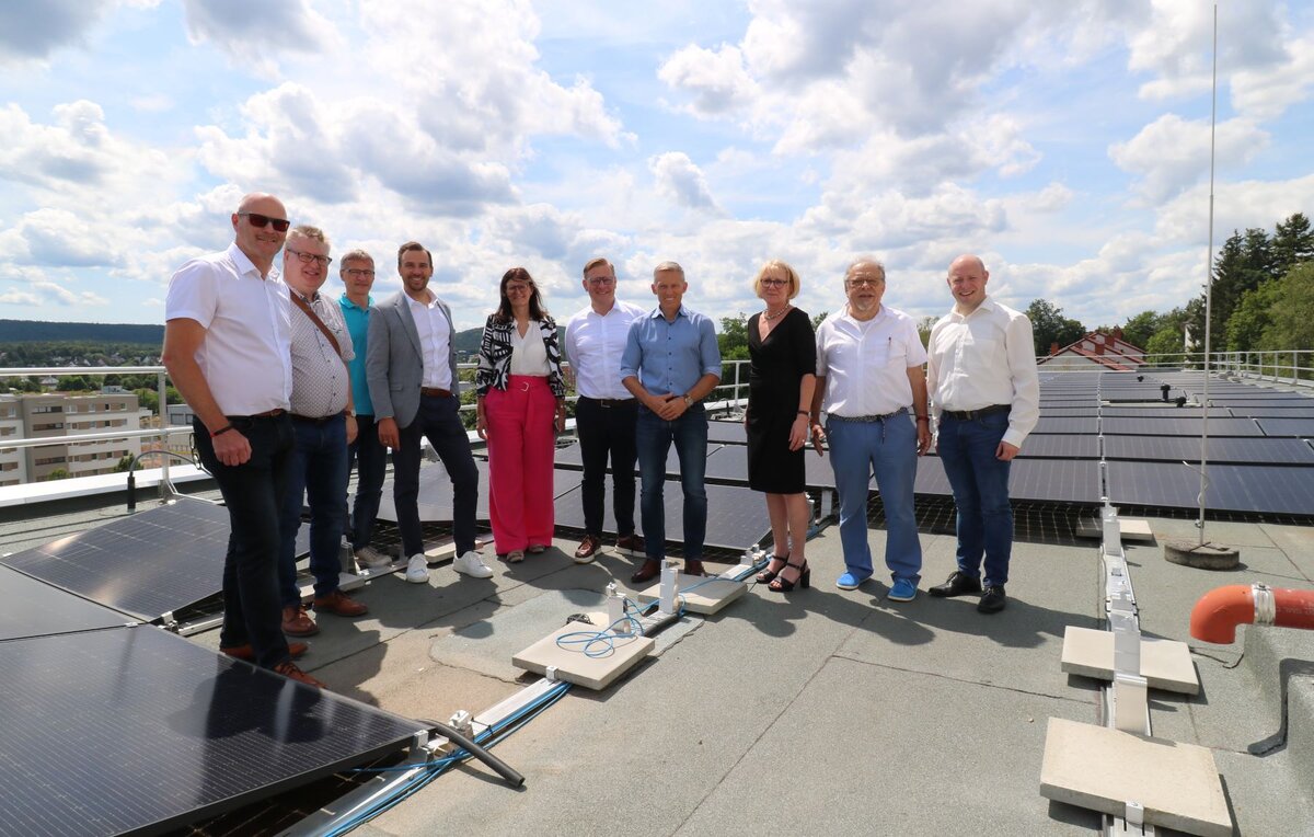 Eine Gruppe von Menschen steht auf dem Dach des Gesundheitsamtes neben der Solaranlage. 