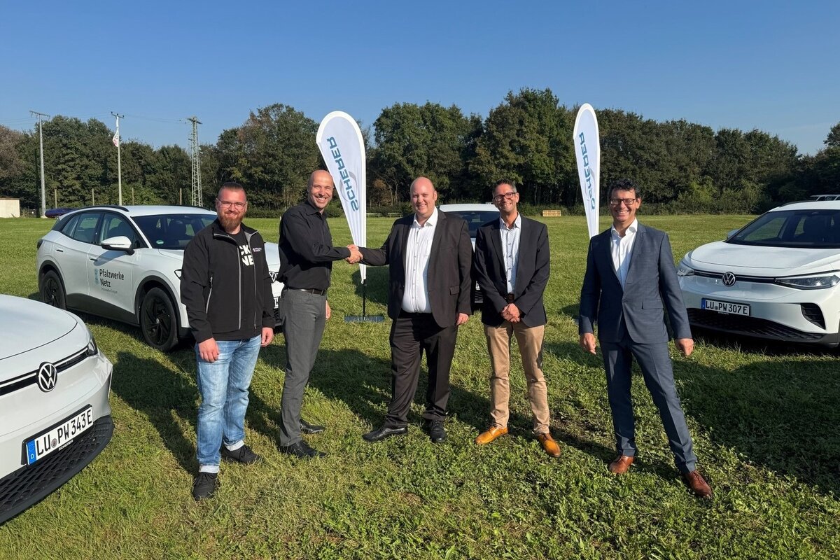 Eine Gruppe von Menschen nimmt die ersten Fahrzeuge der neuen „Elektroflotte“ in Empfang.