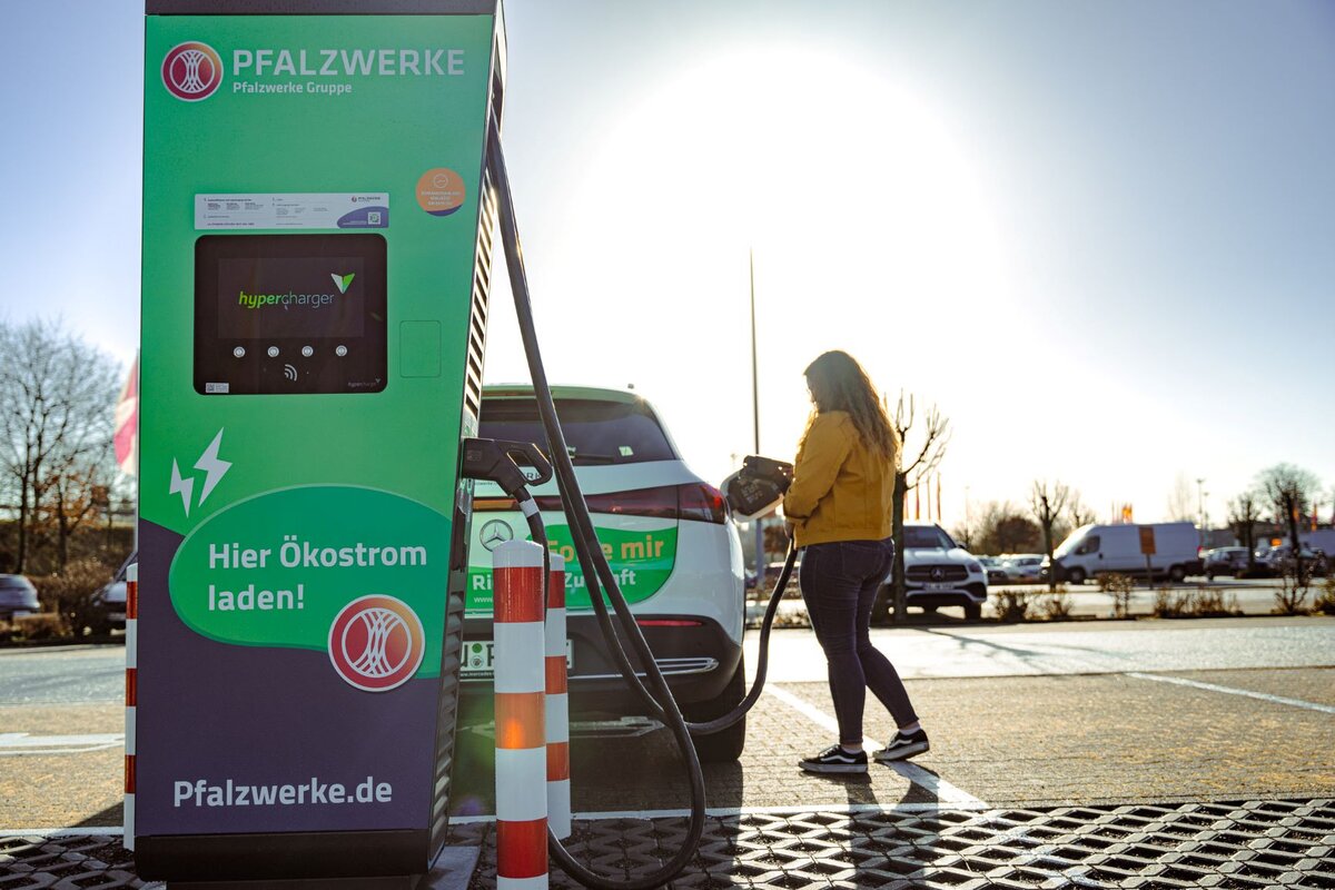 Eine Frau lädt ihr E-Auto an einer Ladesäule. 