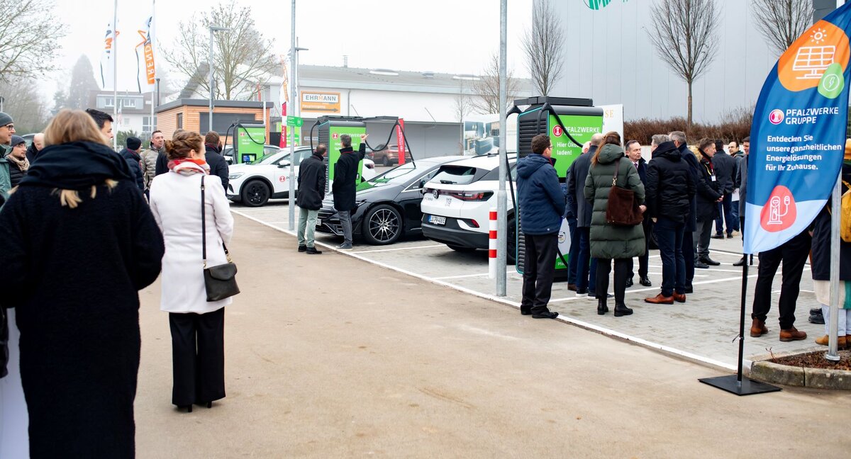 Das Bild zeigt viele Menschen auf einem Parkplatz, die sich den Deutschlandnetz-Ladepark in Landau anschauen.  | © Zahlreiche Besucher schauten sich den Deutschlandnetz-Ladepark in Landau an I Bild: Alexander Grüber
