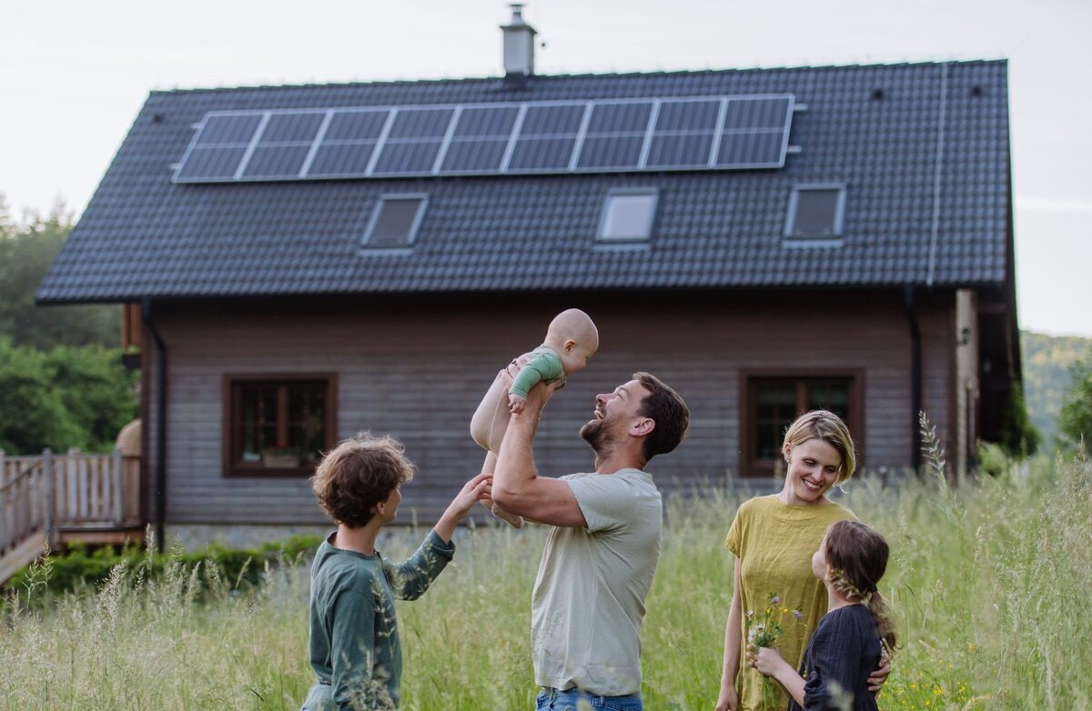 Familie vor Haus im Grünen mit PV-Anlage - Bildnachweis: istock_Halfpoint